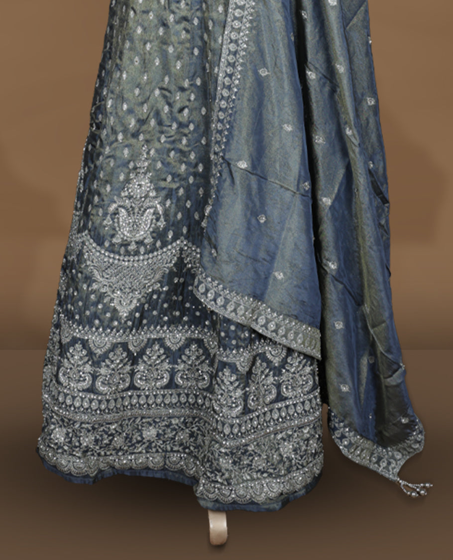 Steel grey and olive ombre effect lehenga set with stitched sleeveless V‑neck embroidered blouse, matching stitched flared lehenga featuring heavy zari and sequin work, and coordinated dupatta with embellished border.