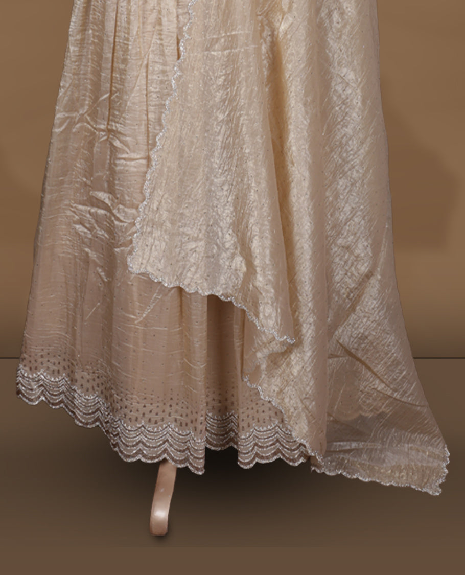 Champagne beige colour stitched gown set with sleeveless embroidered yoke, flared ankle‑length silhouette, and attached dupatta featuring delicate butti work and scalloped beaded edging.