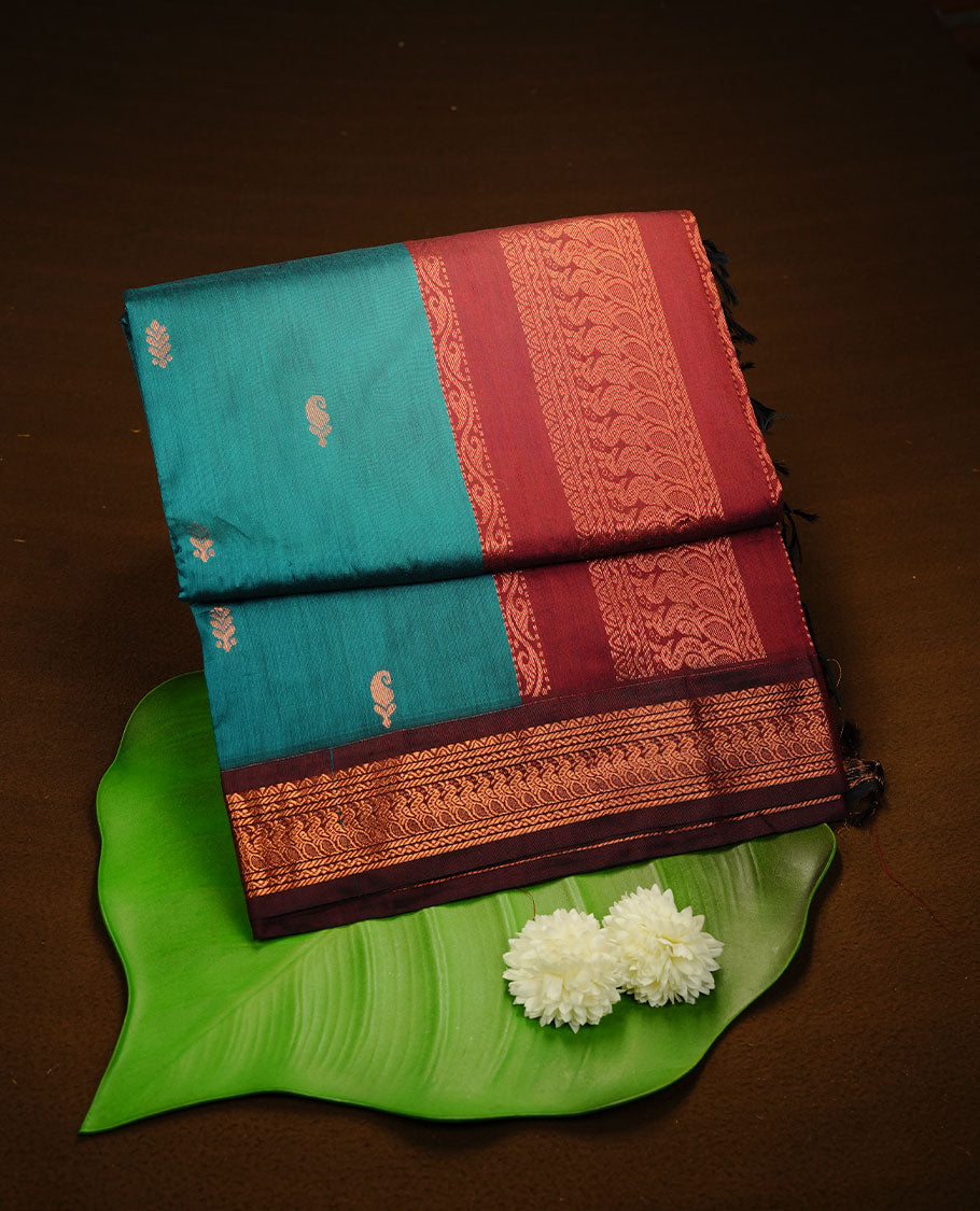 Peacock green colour kalyani cotton saree featuring gold zari motifs on body, complemented by Maroon colour with Antique zari border, paired with matching blouse piece.