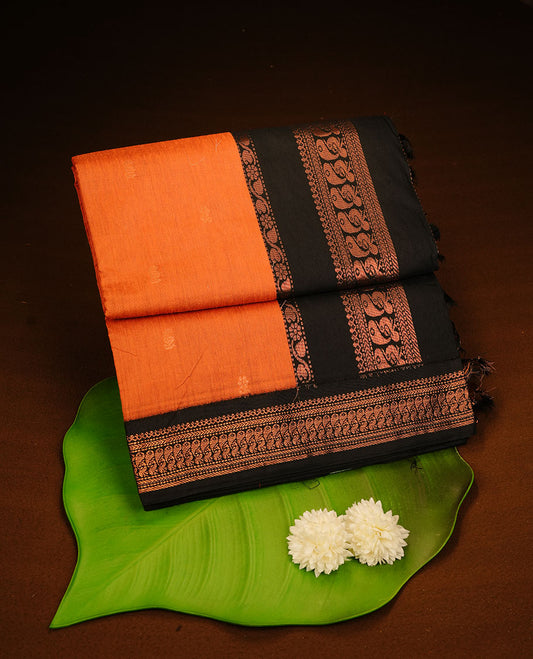 Orange colour kalyani cotton saree featuring antique zari motifs on body, complemented by black colour with Antique zari border, paired with matching blouse piece.