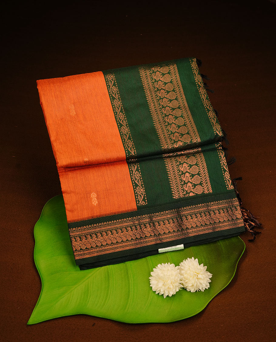 Rust orange colour kalyani cotton saree featuring gold zari motifs on body, complemented by green colour with zari border, paired with matching blouse piece.