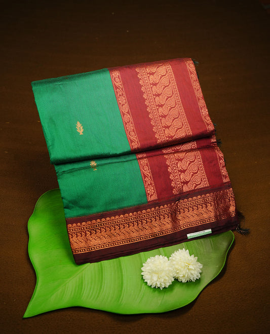Green colour kalyani cotton saree featuring antique zari motifs on body, complemented by Maroon colour with Antique zari border, paired with matching blouse piece.