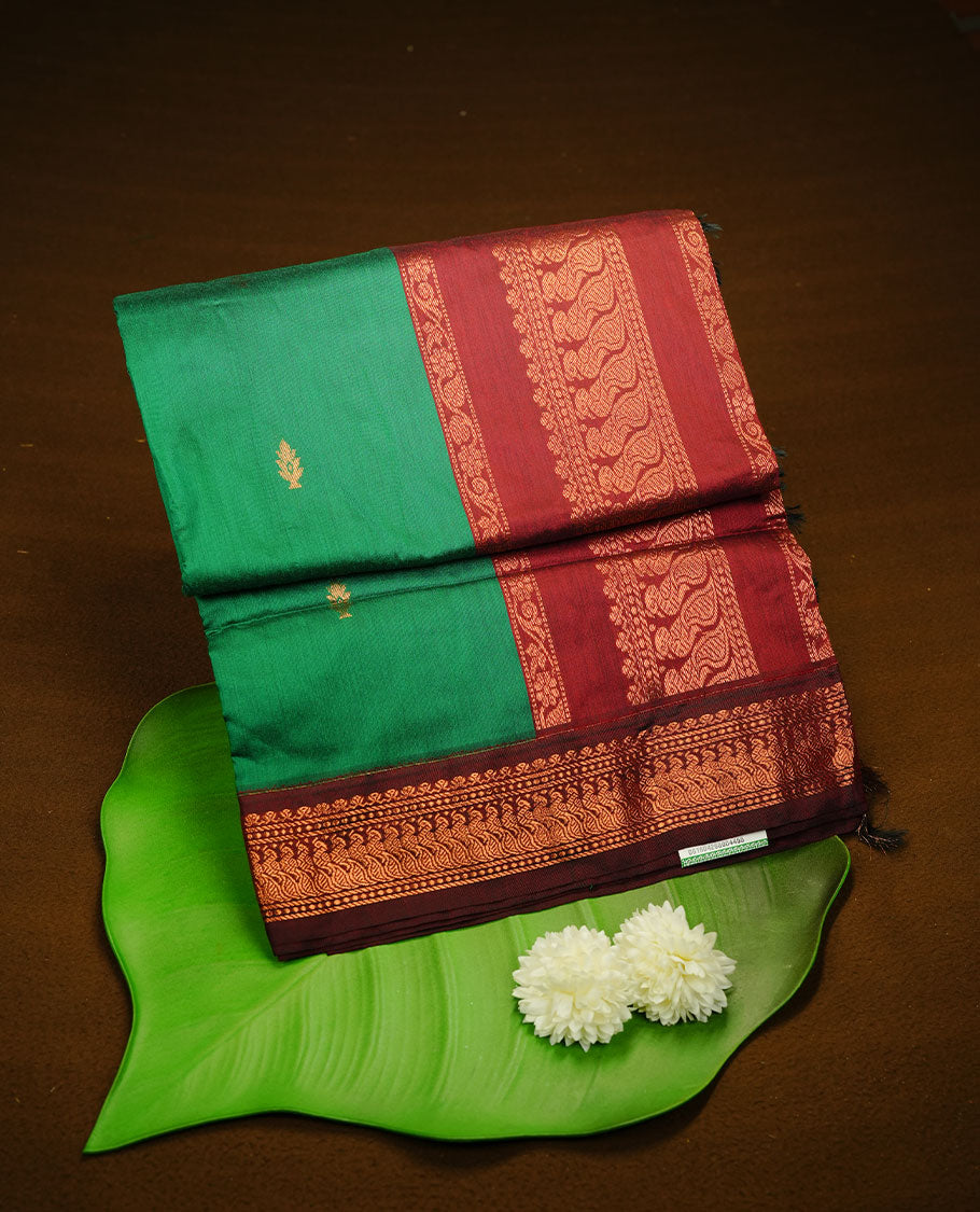 Green colour kalyani cotton saree featuring antique zari motifs on body, complemented by Maroon colour with Antique zari border, paired with matching blouse piece.