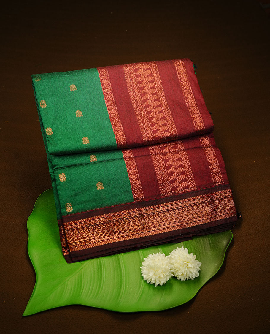Green colour kalyani cotton saree featuring gold zari motifs on body, complemented by Maroon colour with Antique zari border, paired with matching blouse piece.