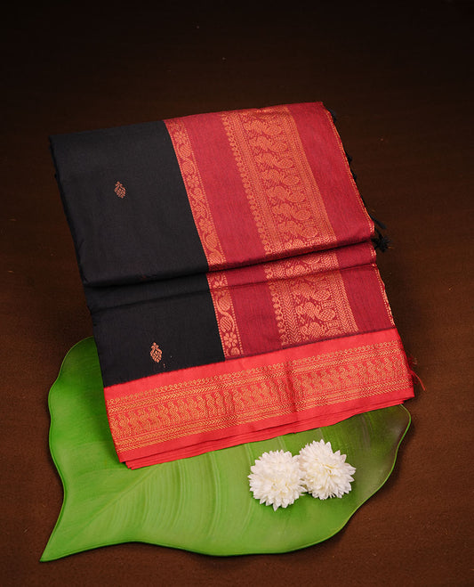 Black colour kalyani cotton saree featuring antique zari motifs on body, complemented by red colour with Antique zari border, paired with matching blouse piece.