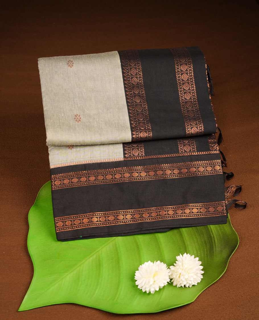 Grey colour kalyani cotton saree featuring gold zari motifs on body, complemented by contrast Black color with copper zari pattern border , paired with matching blouse piece.