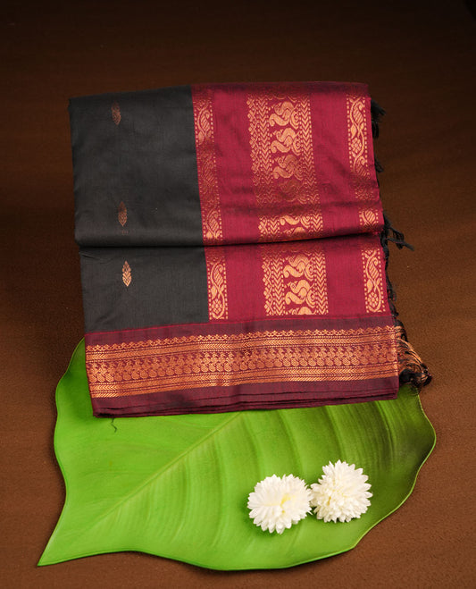 Black colour kalyani cotton saree featuring gold zari motifs on body, complemented by contrast maroon color with copper zari pattern border , paired with matching blouse piece.