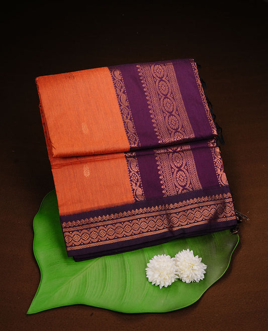 Orange colour kalyani cotton saree featuring Elegant plain body, complemented by Purple colour with Antique zari border, paired with matching blouse piece.