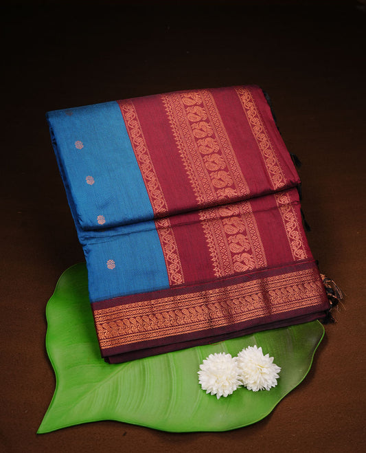 Blue colour kalyani cotton saree featuring antique zari motifs on body, complemented by Maroon colour with Antique zari border, paired with matching blouse piece.