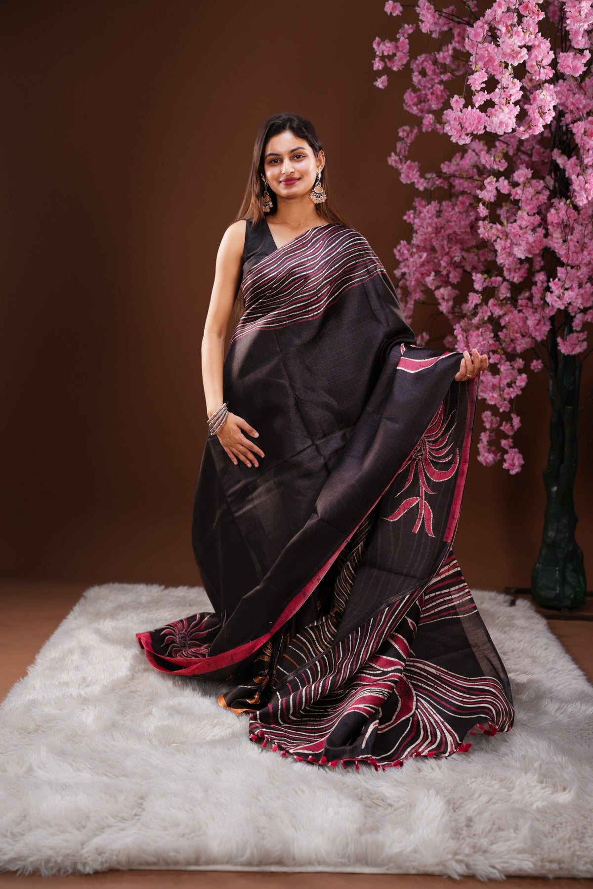 Black colour Semi Khadi Silk Saree featuring a plain black body, complemented by a peach colour geometric pattern on border and paired with a matching blouse piece.