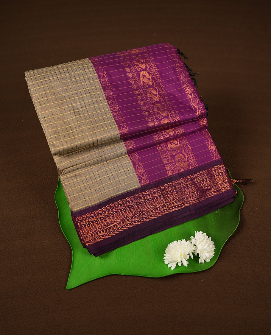 Khaki coloured mixed Kalyani cotton saree featuring copper zari checks on the body, complemented by a rich grape coloured border and pallu adorned with copper zari patterns, Paired with a matching blouse.