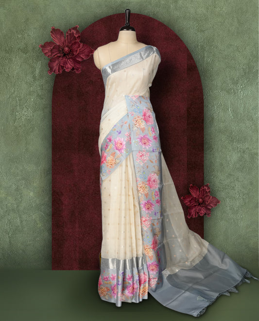 Ivory colour Kotta Tussar Silk saree features a vibrant digital floral print with small gold zari motifs on the body, and elegant grey colour banarasi border & Paired with a matching blouse,blending modern design with traditional elegance.