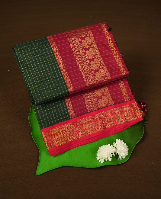 Dark Green coloured mixed Kalyani cotton saree featuring golden zari checks on the body, complemented by a dark red coloured border and pallu adorned with golden zari patterns, Paired with a matching blouse.