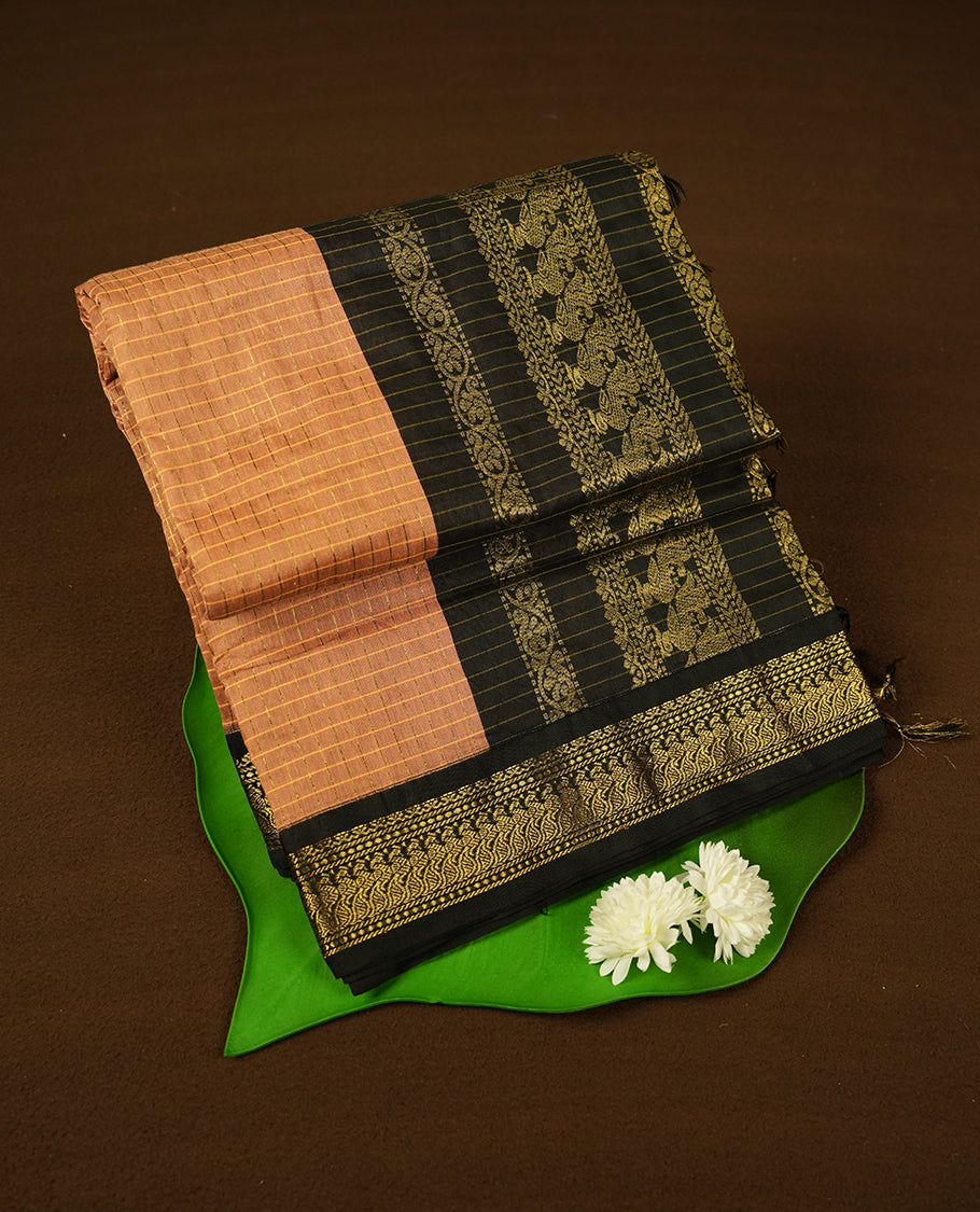 Burnt orange coloured mixed Kalyani cotton saree featuring golden zari checks on the body, complemented by a black coloured border and pallu adorned with golden zari patterns, Paired with a matching blouse.