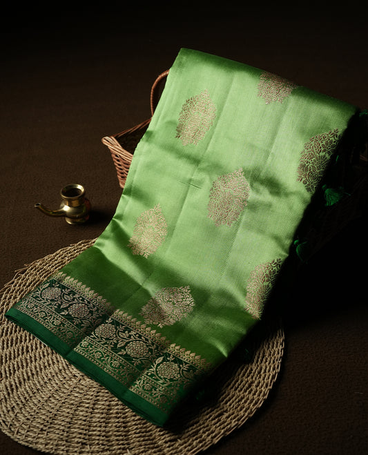 Green Colour Banaras Soft Silk Saree with Gold Zari Round Cluster Buttas, Intricate Multi-Layered Floral Border, Grand Pallu with Ornate Brocade Motifs in Deep Green and Gold Tones, and Matching Blouse.