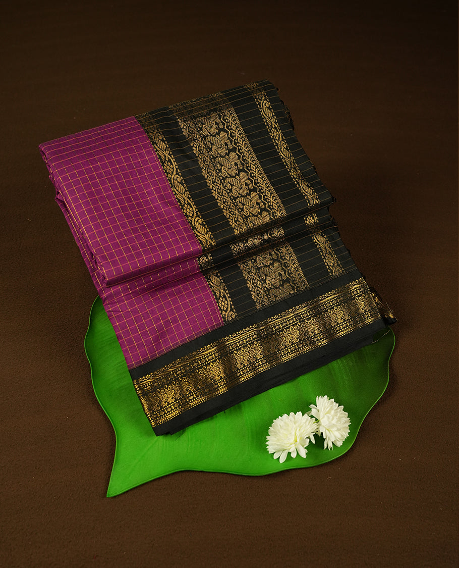 Grape coloured mixed Kalyani cotton saree featuring golden zari checks on the body, complemented by a black coloured border and pallu adorned with golden zari patterns, Paired with a matching blouse.