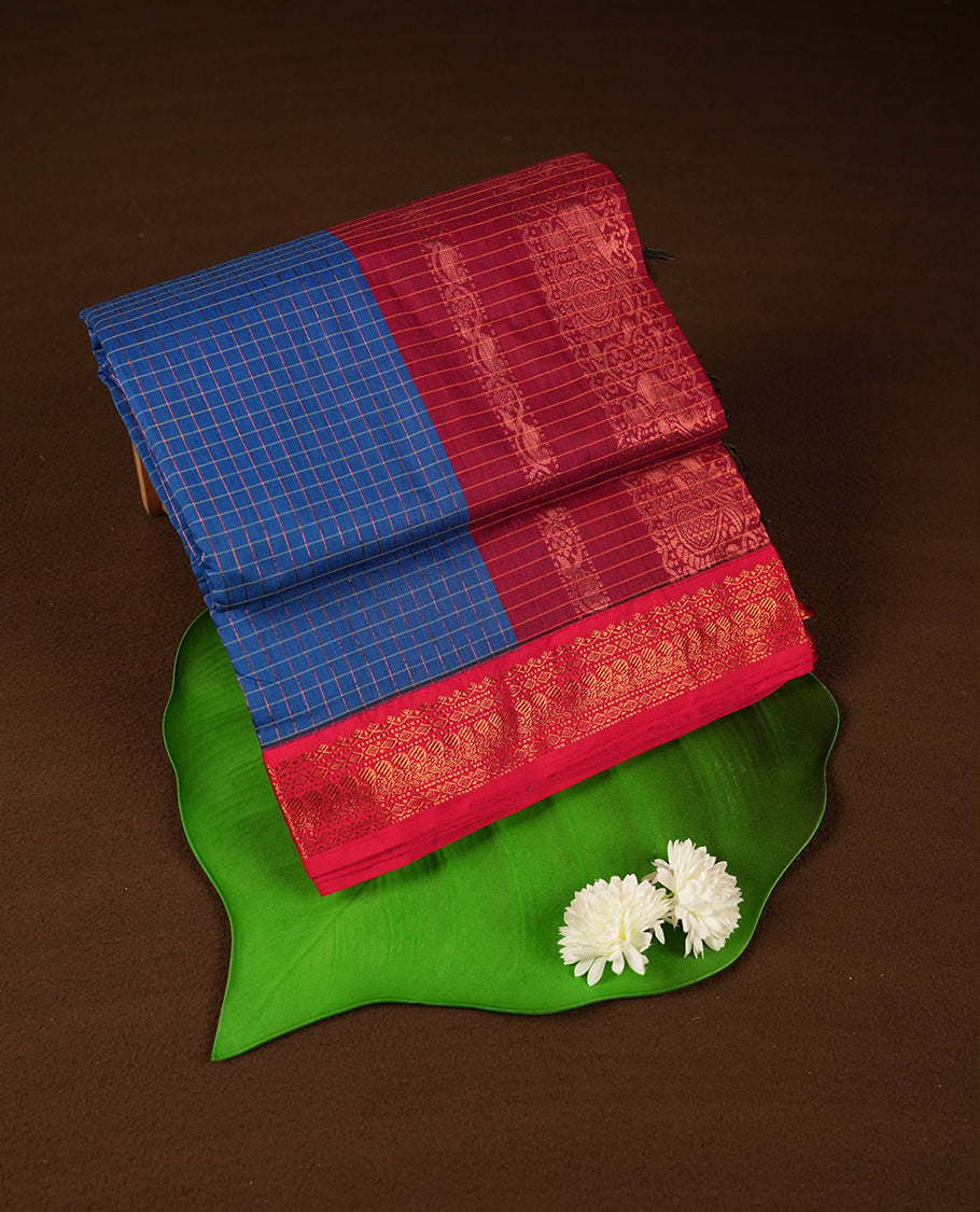 Royal Blue coloured mixed Kalyani cotton saree featuring copper zari checks on the body, complemented by a Dark red coloured border and pallu adorned with copper zari patterns, Paired with a matching blouse.