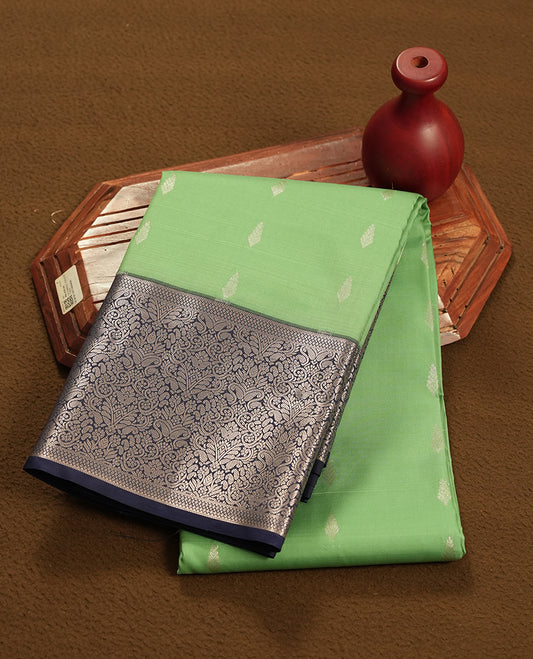 Jade green colour semi soft silk saree featuring a golden textured patterned body, complemented by contrast navy blue with silver zari motifes on pallu & border and a matching blouse piece.