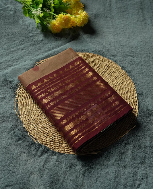 Beige Colour silk cotton saree with scattered maroon and black buttas, ornate maroon and gold zari border with geometric patterns, gold zari pallu with diamond lattice, plain beige blouse with maroon border.