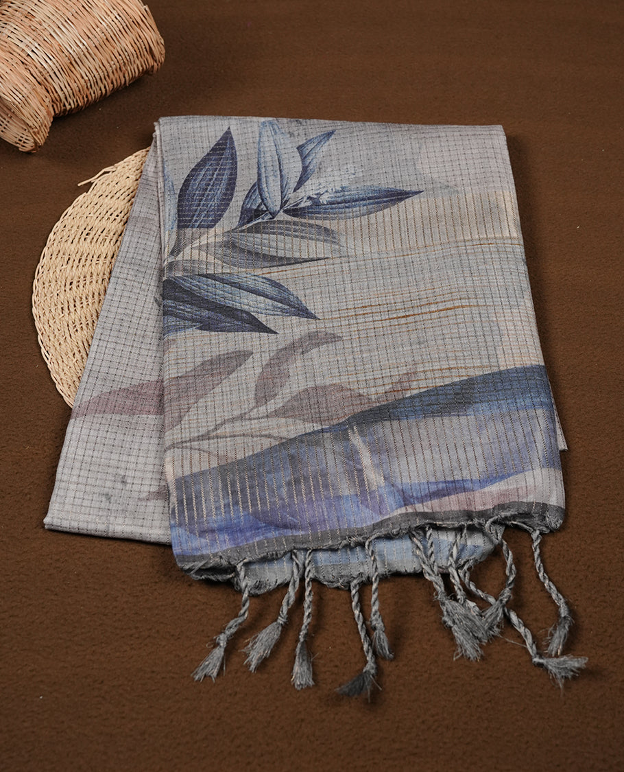 Blue grey colour semi tussar silk saree featuring floral print across body, contrast dark blue colour border and pallu, paired with matching blouse piece.