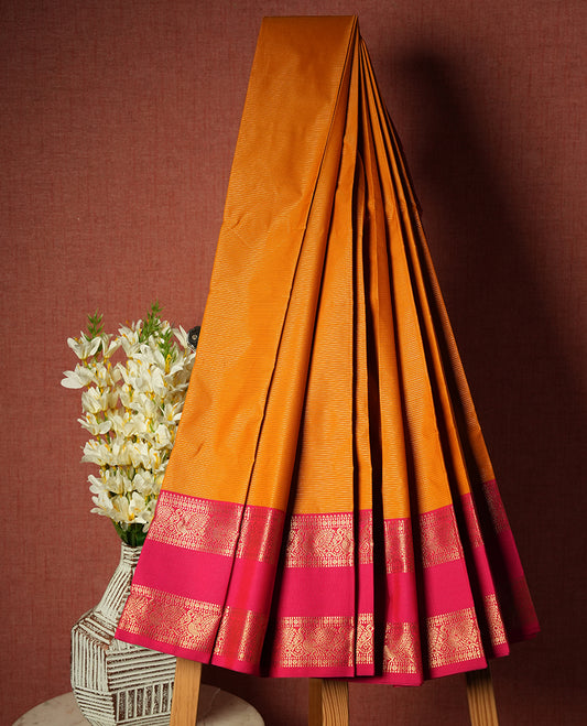 Harvest gold colour Semi Silk Saree with gold zari striped patterns on the body, paired with a contrasting rani pink colour traditional pallu and border, and a matching blouse piece.