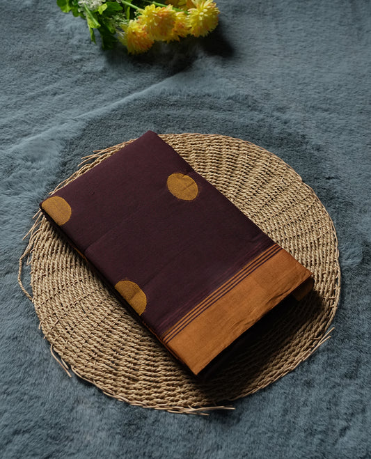 Dark Brown colour Silk Cotton Saree with Mustard Orange Circular Buttas on the Body, Contrasting Antique Gold Zari Pallu Featuring Intricate Floral and Geometric Motifs with Temple-Style Borders, Paired with a Coordinated Blouse Piece