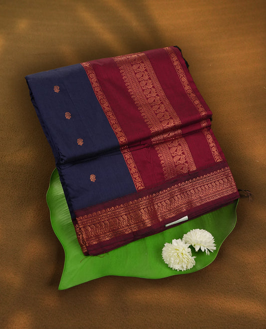 Navy blue colour Kalyani Cotton saree with deep maroon border and pallu, adorned with copper zari peacock motifs and intricate weaving & Comes with a matching blouse piece.