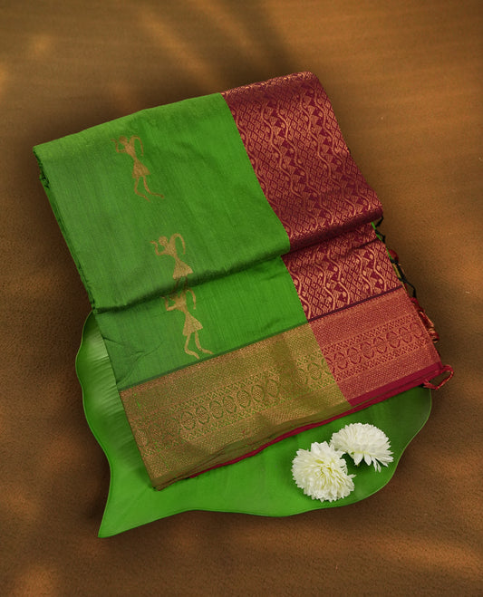 Green and maroon Kalyani cotton saree featuring elegant dancer motifs on the body with golden zari, complemented by a rich contrast zari border and paired with a matching blouse.