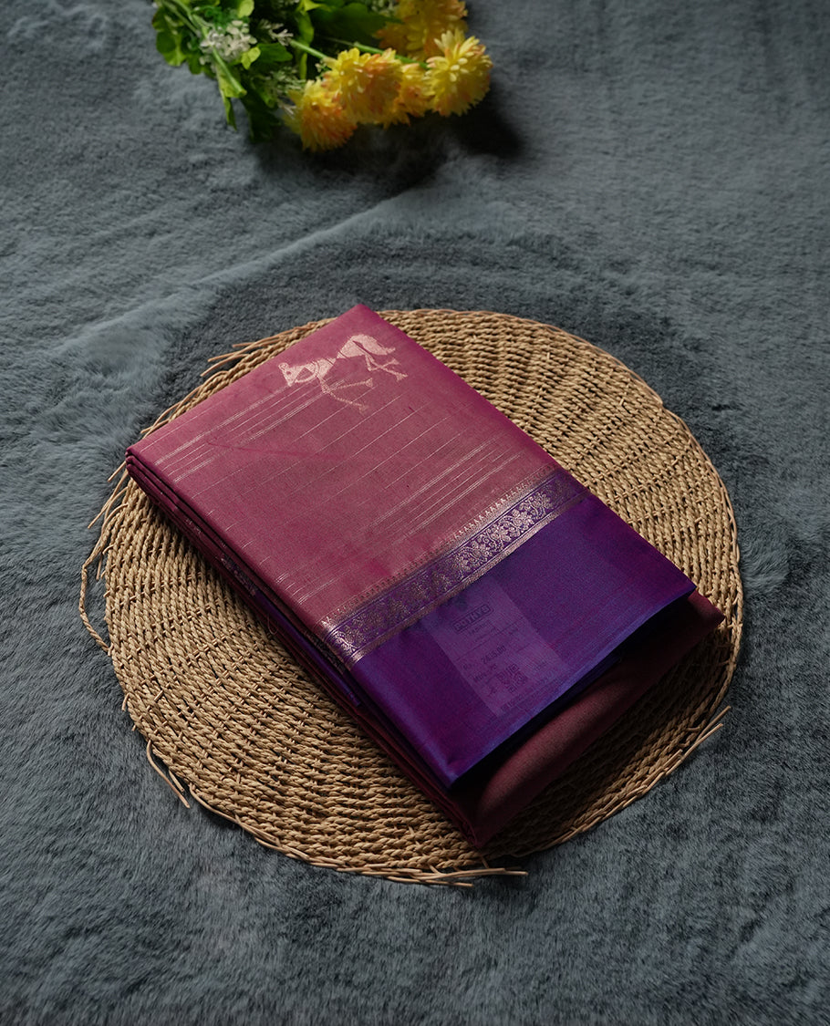 Rose Mauve and Royal Purple Colour silk cotton saree with Warli dancer pallu, subtle pinstripes and pastoral buttas on the body, floral zari border along the purple edge, and a coordinated Rose Mauve blouse with border.
