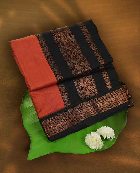 Orange colour Kalyani Cotton saree with rich black border and pallu, featuring copper zari peacock motifs and intricate weaving & Includes a matching blouse piece.