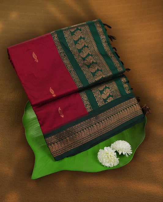 Maroon colour Kalyani Cotton saree with deep green border and pallu, adorned with copper zari motifs and intricate weaving & Comes with a matching blouse piece.