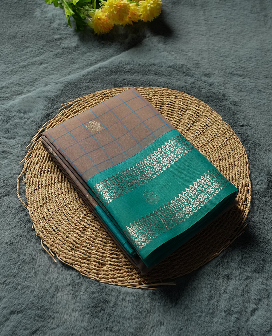 Beige Colour silk cotton saree with checkered body, scattered silver zari leaf buttas, ornate silver zari borders in teal green, diamond lattice pallu with temple motifs, teal green blouse with matching border.