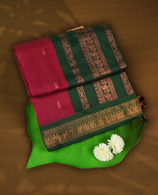 Maroon colour Kalyani cotton saree with  zari motifs all over, paired with a contrasting green rich peacock copper zari woven border and pallu & comes with a matching blouse piece.
