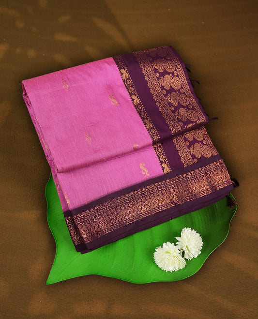 Pink colour Kalyani cotton saree with subtle zari motifs all over, paired with a contrasting plum wine colour rich copper zari woven border and pallu & Comes with a matching blouse piece.