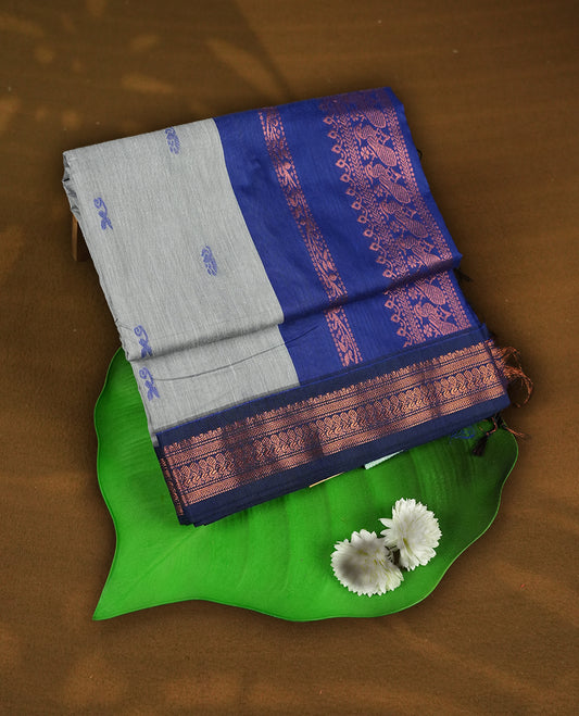 Grey colour Kalyani Cotton saree with woven zari royal blue floral motifs all over, paired with a contrasting royal blue border, floral & birds work on pallu intricately woven with rich copper zari & Comes with a matching blouse piece.