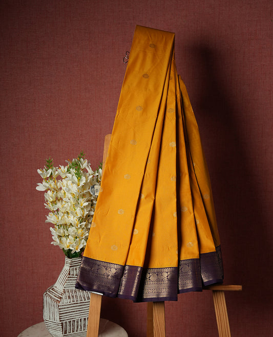 Yellow colour Semi Silk Saree with gold zari striped patterns on the body, paired with a contrasting dark purple colour traditional pallu and border, and a matching blouse piece.