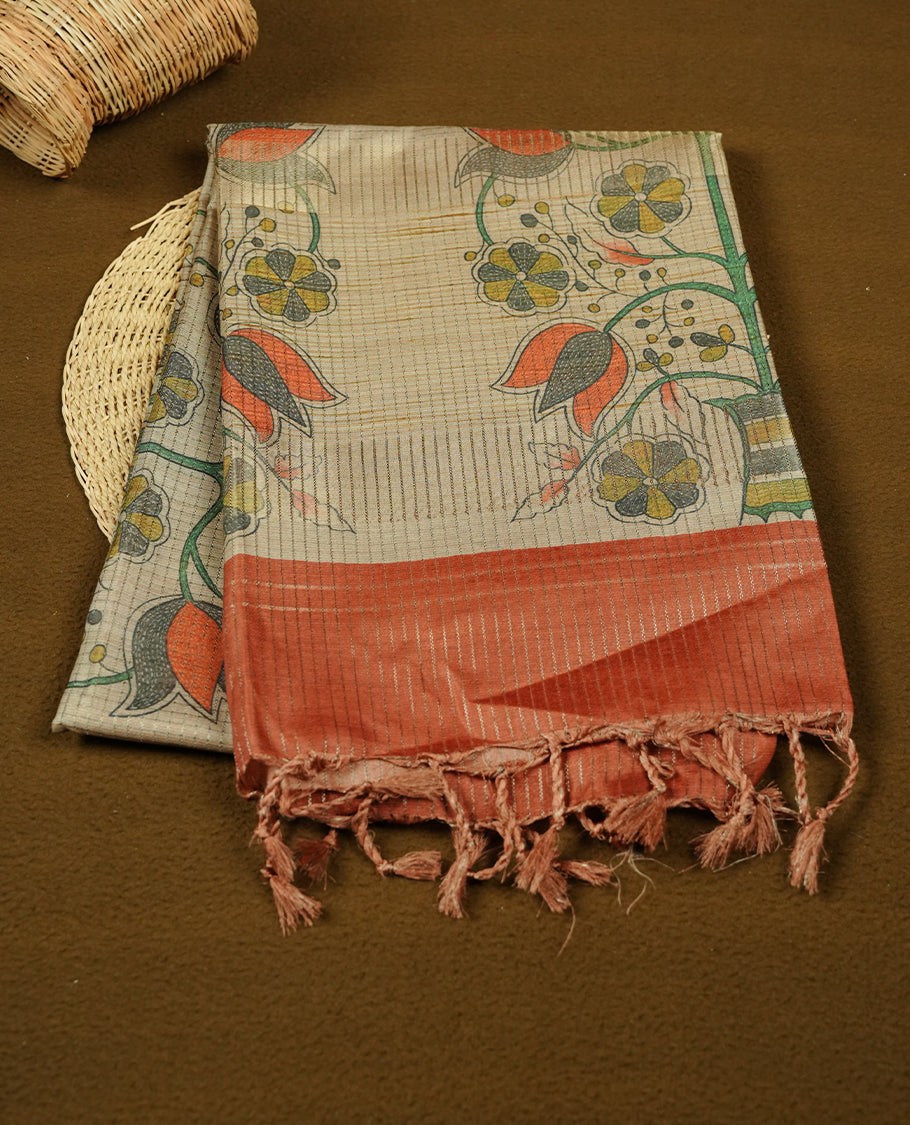 Wheat colour semi tussar silk saree featuring floral print and zari check pattern across body, contrast burnt orange colour border and pallu, paired with matching blouse piece.