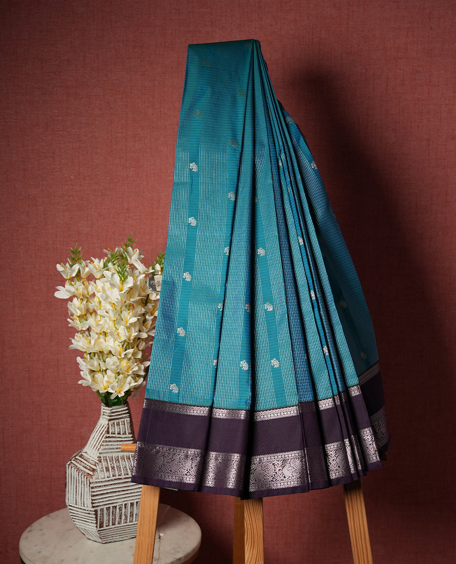 Aqua blue colour Semi Silk Saree with silver zari patterns on the body, paired with a contrasting dark violet colour traditional pallu and border, and a matching blouse piece.