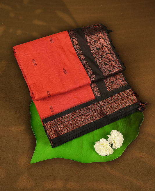 Burnt orange colour Kalyani Cotton saree with delicate woven zari black motifs all over, paired with a contrasting black border and pallu intricately woven with rich copper zari & Comes with a matching blouse piece.