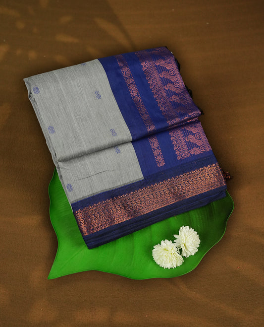 Grey colour Kalyani Cotton saree with delicate woven zari royal blue motifs all over, paired with a contrasting royal blue border and pallu intricately woven with rich copper zari & Comes with a matching blouse piece.