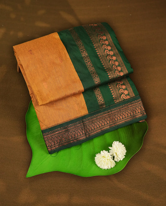 Mustard yellow colour Kalyani Cotton saree with delicate woven zari motifs all over, paired with a contrasting deep green border and pallu intricately woven with rich copper zari & Comes with a matching blouse piece.