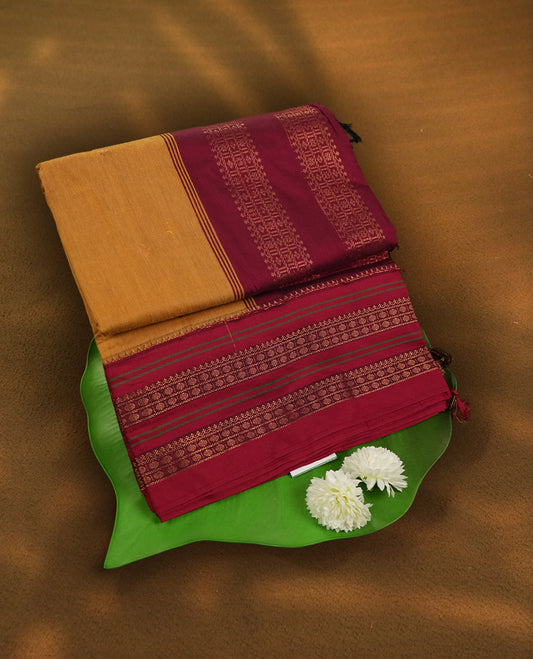 Mustard yellow Kalayani cotton saree with delicate woven motifs on the body, enhanced by a rich maroon contrasted zari border and pallu with traditional patterns, paired with a matching blouse piece.