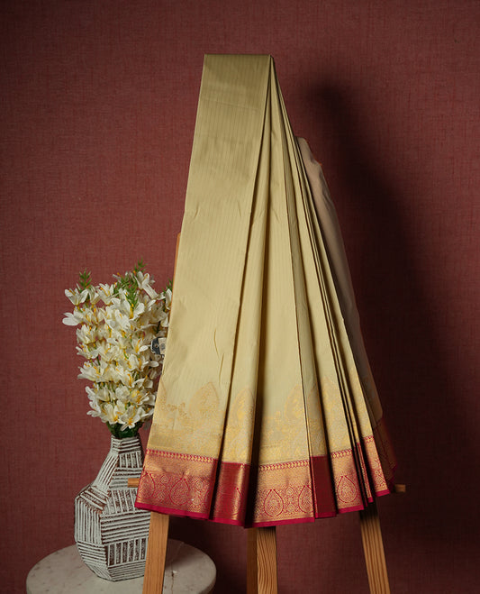 Ivory Semi Silk Saree with gold zari striped body and peacock motifs, complemented by a contrasting rani pink pallu and border in gold zari with traditional motifs, paired with a matching blouse piece