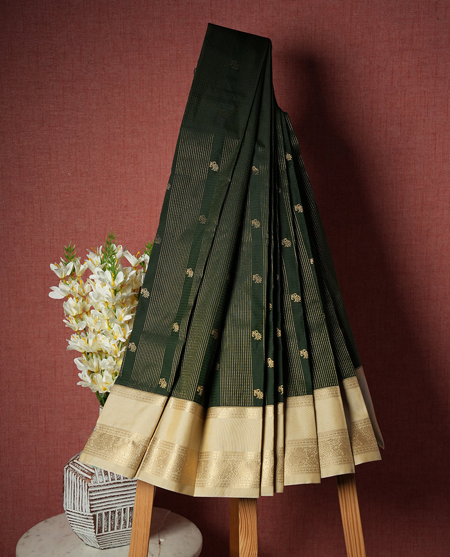 Dark green colour Semi Silk Saree with gold zari striped patterns on the body, paired with a contrasting cream colour traditional pallu and border, and a matching blouse piece.