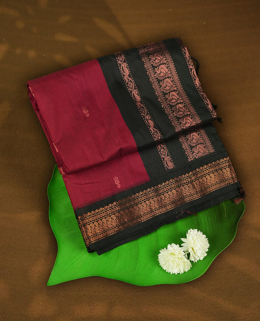 Maroon colour Kalyani cotton saree with subtle zari motifs all over, paired with a contrasting black rich copper zari woven border and pallu & Comes with a matching blouse piece.