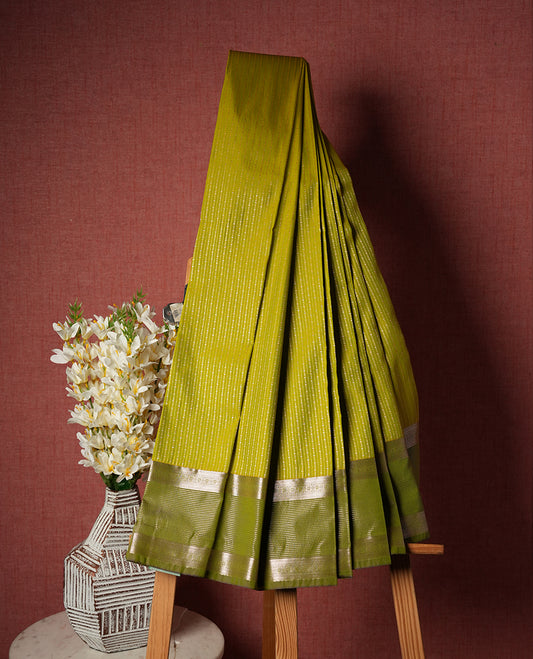 Lemon green Colour Semi Silk Saree with gold zari stripes on the body, paired with a contrasting olive colour pallu and border, and a matching blouse piece.