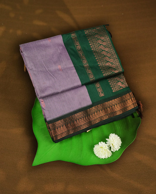 Soft Lavender colour Kalyani Cotton saree with delicate woven zari buttas all over, paired with a contrasting deep bottle green border and pallu intricately woven with rich copper zari & Comes with a matching blouse piece.