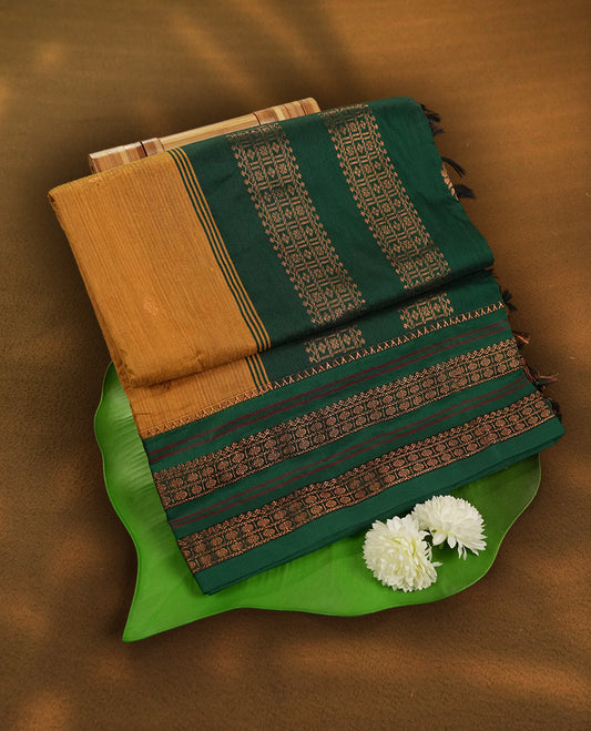 Mustard yellow Kalayani cotton saree with delicate woven motifs on the body, enhanced by a rich green zari border and pallu with traditional patterns, paired with a matching blouse piece.
