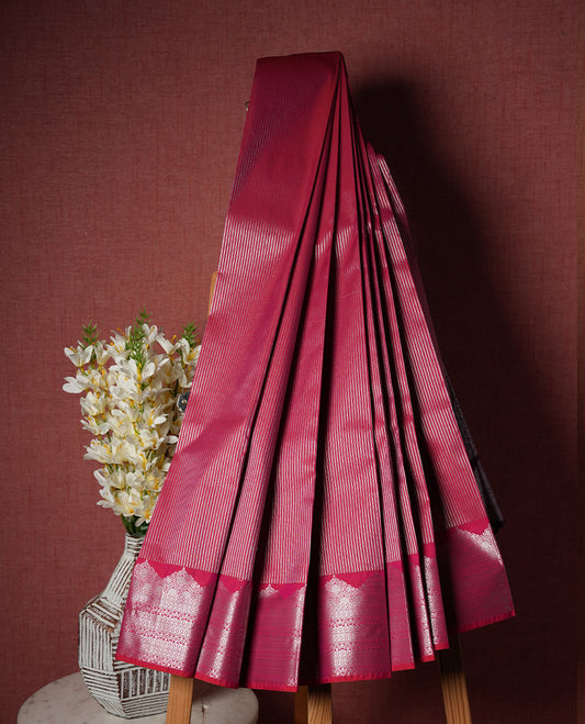 Rani pink colour Semi Silk Saree with silver zari striped patterns on the body, paired with a contrasting dark purple  traditional pallu and border, and a matching blouse piece.