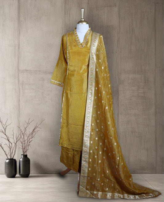 Golden yellow salwar from TWARA, featuring a V neck with delicate sequin highlights and plain finish on the top, paired with a matching bottom and a rich Banarasi style dupatta adorned with zari motifs and a contrast border.